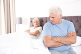 Mature couple with relationship problems ignoring each other in bedroom