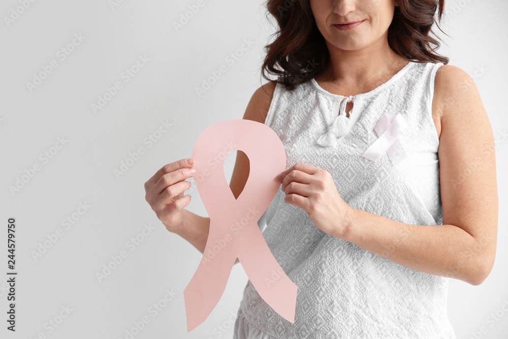 Woman holding pink paper ribbon against white background, closeup. Breast cancer awareness concept Woman holding pink paper ribbon against white background, closeup. Breast cancer awareness concept