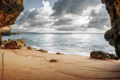 beautiful Atlantic ocean view horizon with sandy beach,  rocks and waves. Algarve,  Portugal