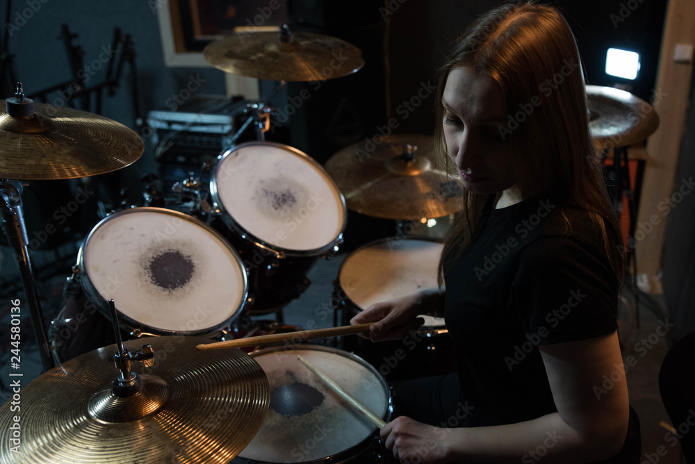 Professional drum set closeup. Beautiful young girl drummer with drumsticks playing drums and cymbals, on the live music rock concert or in recording studio Professional drum set closeup. Beautiful young girl drummer with drumsticks playing drums and cymbals, on the live music rock concert or in recording studio