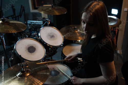 Professional drum set closeup. Beautiful young girl drummer with drumsticks playing drums and cymbals, on the live music rock concert or in recording studio 
