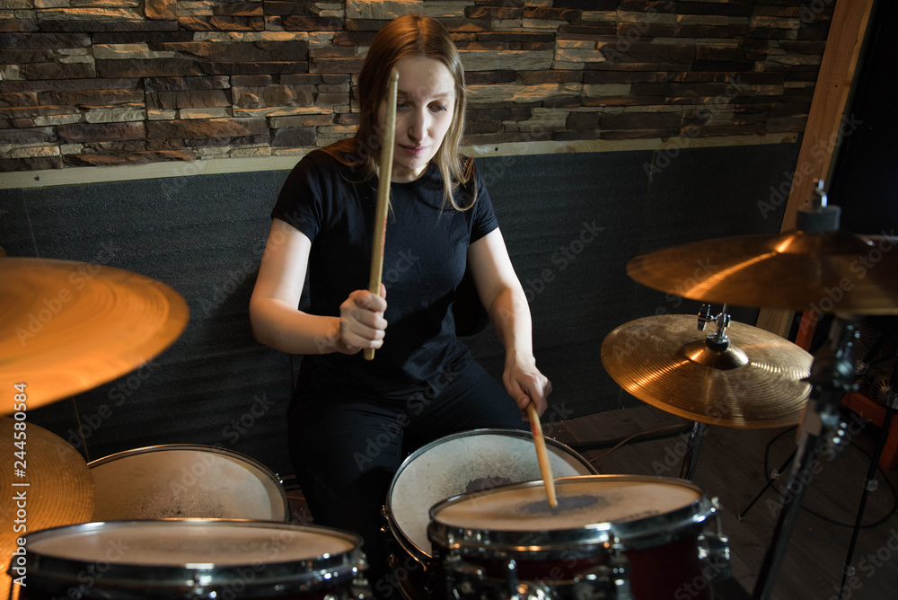 Obraz premium Professional drum set closeup. Beautiful young girl drummer with drumsticks playing drums and cymbals, on the live music rock concert or in recording studio 