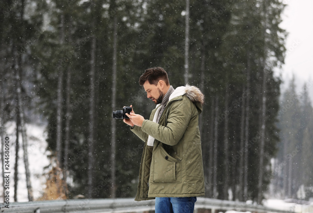Man with camera walking near forest on snowy winter day Man with camera walking near forest on snowy winter day