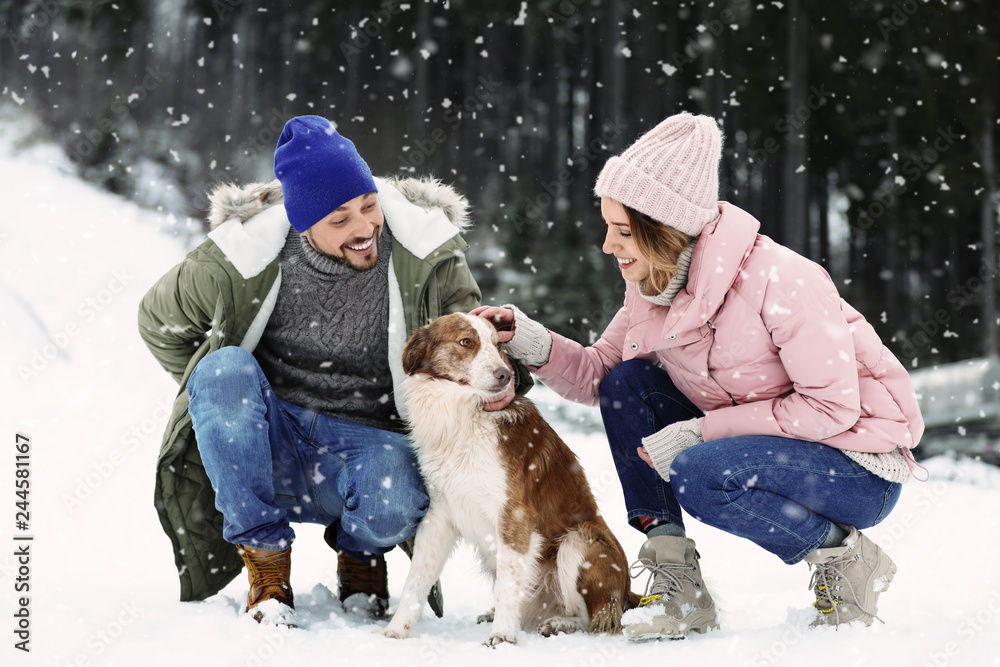 Cute couple with dog outdoors. Winter vacation
