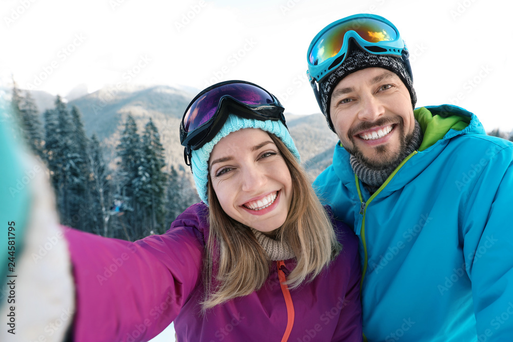 Happy couple taking selfie during winter vacation in mountains Happy couple taking selfie during winter vacation in mountains