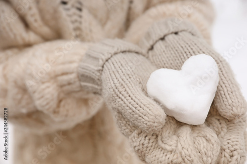 Woman holding heart made of snow, closeup view