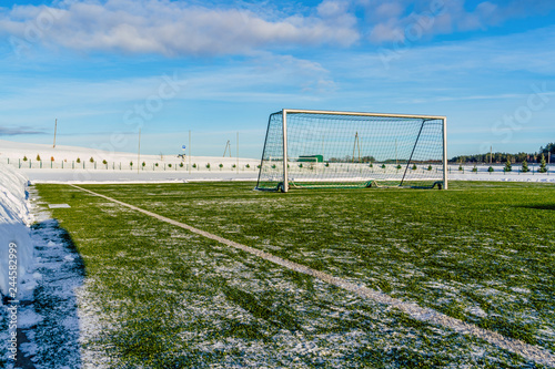 Empty Football (Soccer) Field in the Winter Partly Covered in Snow - Sunny Winter Day