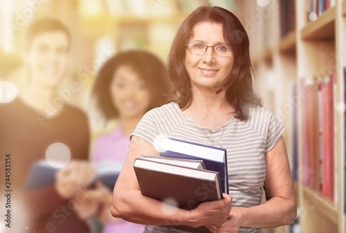 Mature woman teacher with books on background