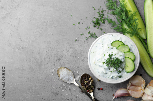 Cucumber sauce with ingredients on grey background, flat lay. Space for text photo