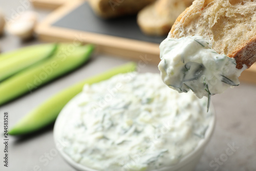 Bread in cucumber sauce on blurred background, space for text. Traditional Tzatziki