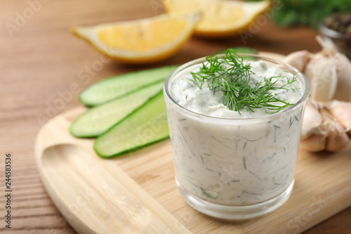 Cucumber sauce with ingredients on wooden background, space for text. Traditional Tzatziki