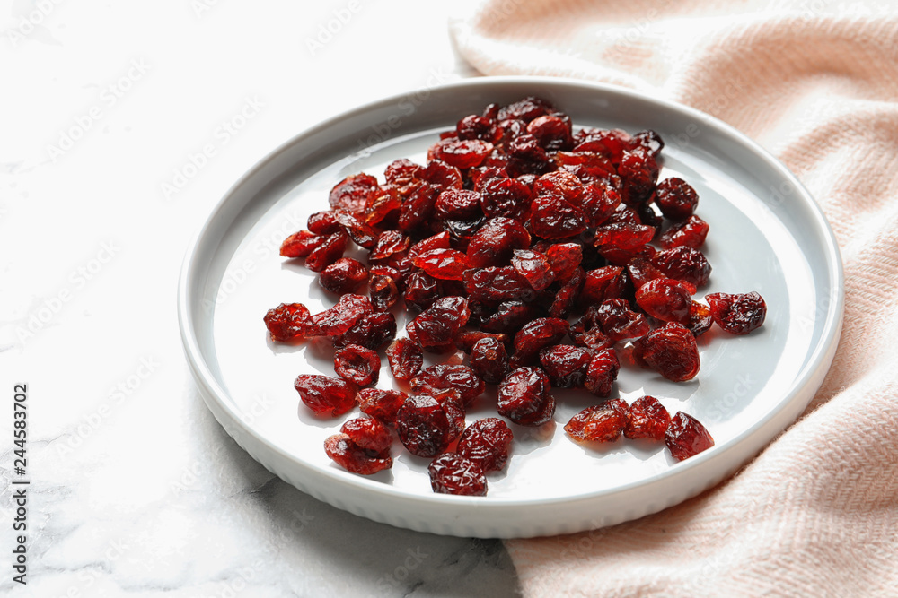 Plate with cranberries on marble table. Dried fruit as healthy snack Plate with cranberries on marble table. Dried fruit as healthy snack