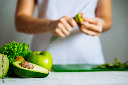 green fruits on front. woman cut fruits on background. healthy food concept