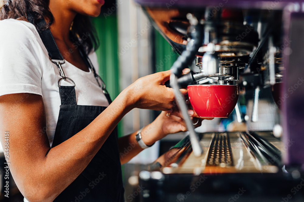 Unrecognizable female barista using a coffee maker to prepare a espresso Unrecognizable female barista using a coffee maker to prepare a espresso
