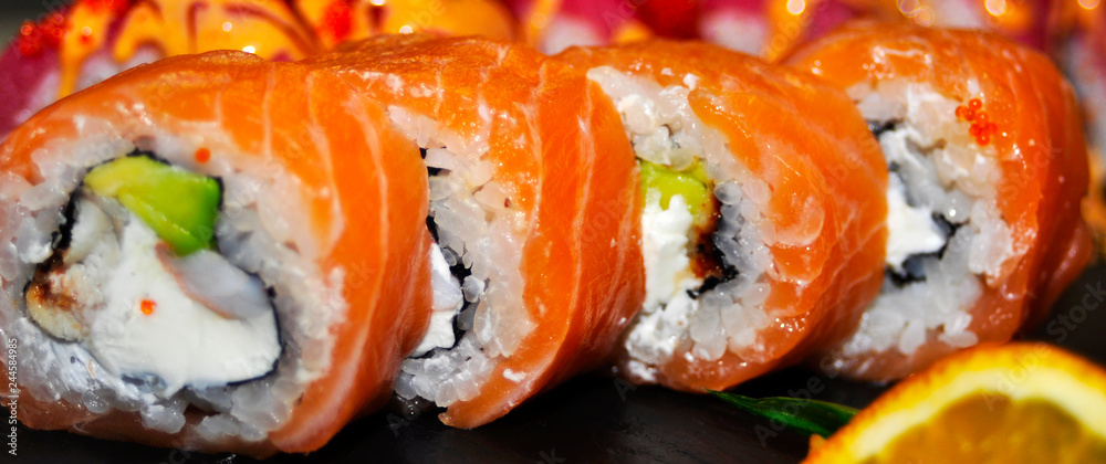 Eating Sushi with chopsticks. Sushi roll japanese food in restaurant. California Sushi roll set with salmon, vegetables, flying fish roe and caviar closeup. Japan restaurant menu Eating Sushi with chopsticks. Sushi roll japanese food in restaurant. California Sushi roll set with salmon, vegetables, flying fish roe and caviar closeup. Japan restaurant menu