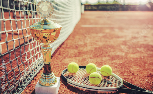 Tennis balls with a racket and cup on the tennis court. Sport, recreation concept photo