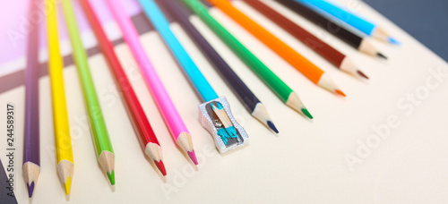Colour pencils with sharpener lying on pastel beige background. Back to school concept. Colorful art studying and painting process. Drawing with pencils. Copy space place for postcard wish.
