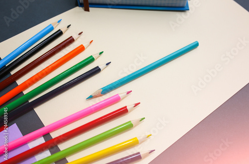 Colour pencils with notebooks and lying on pastel beige background. Back to school concept sign written. Colorful art studying and painting process.