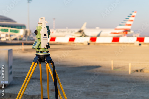 Surveyor equipment (theodolite) on construction site of the airport, building or road with construction machines in background