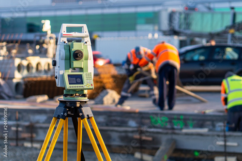 Surveyor equipment (theodolite) on construction site of the airport, building or road with construction machines in background photo