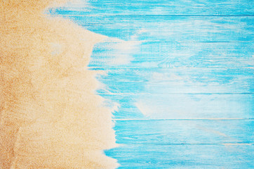Top view of sandy beach and marine blue planks pier. Background with copy space and visible sand and wood texture.