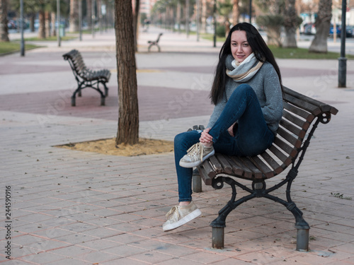 young brunette girl sitting on a bench and smiling