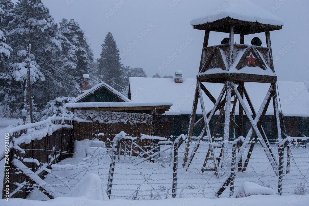 A watchtower with the fence in the middle of the snow covered forest. A watchtower with the fence in the middle of the snow covered forest.