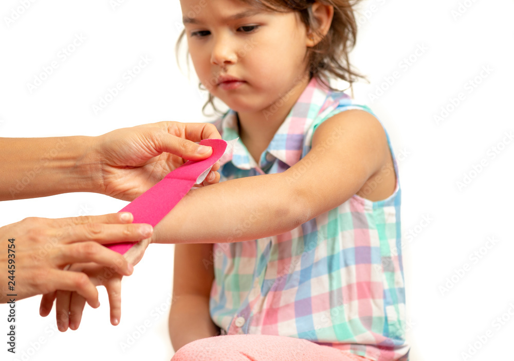 Mother applying kinisiology tape to her daughter injury hand Mother applying kinisiology tape to her daughter injury hand