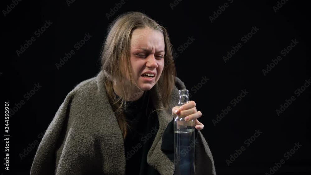 Female beggar with bruises on face drinking vodka with disgust alcohol addiction
