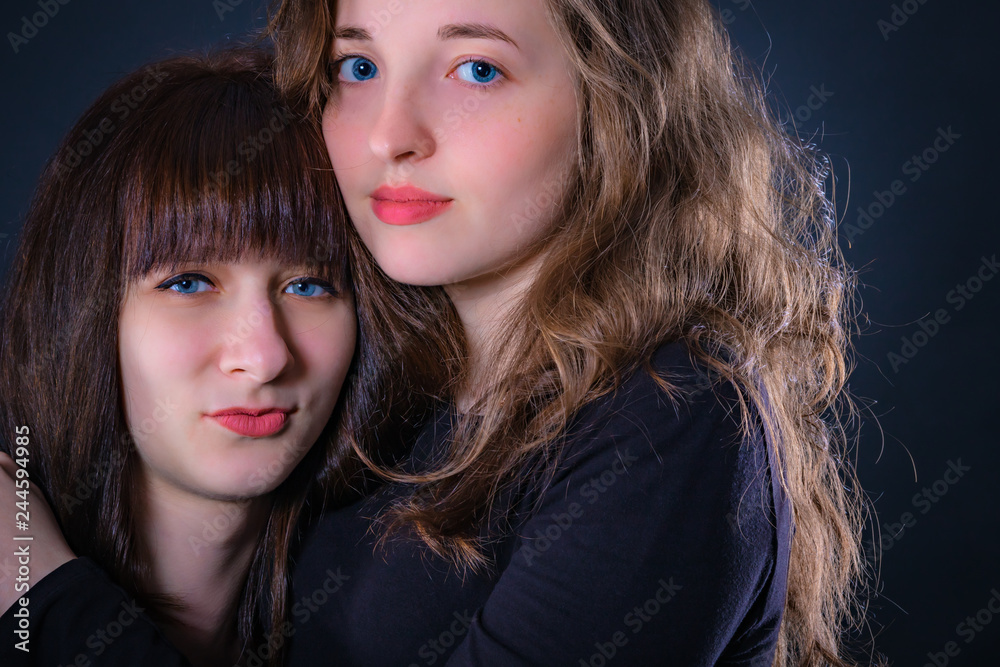 Naklejka premium Group portrait of two girls on a dark background