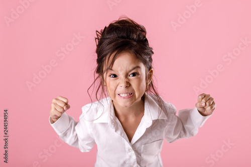 Photography angry little child girl in white shirt with hairstyle