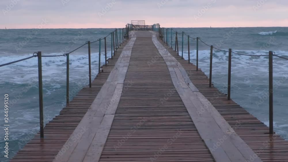 Waves splashes through the wooden pier in the sea. Beautiful seascape at sunset. Waves splashes through the wooden pier in the sea. Beautiful seascape at sunset.