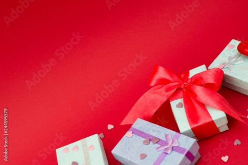 Many colorful gift boxes on red background. Valentine's day, mother's Day, birthday or party concept. Hearts decorations. Copy space.