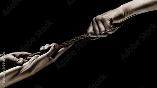 Hand holding a rope, climbing rope, strength and determination. Rescue, help, helping gesture or hands. Conflict, tug of war. Two hands, helping hand, arm, friendship. Teamwork, friendship. Rope, cord
