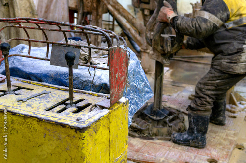 Offshore oil rig worker prepare tool and equipment for perforation oil and gas well at wellhead platform. Making up a drill pipe connection. A view for drill pipe connection from between the stands. photo