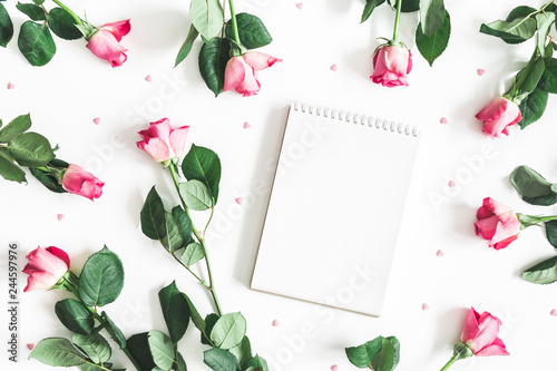 Flowers composition. Pink rose flowers, notebook on white background. Flat lay, top view, copy space