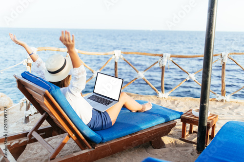 Young and beautiful woman with raised hands with the laptop relaxing on the beach © F8  \ Suport Ukraine