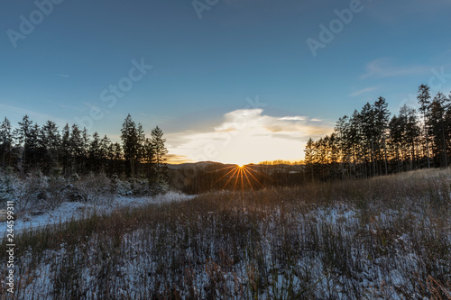 Wunderschöner Sonnenuntergang über winterlichen Wäldern © scaleworker
