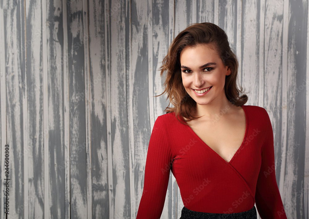 Fototapeta premium Beautiful positive toothy smiling woman and looking happy in casual red shirt and short curly hair