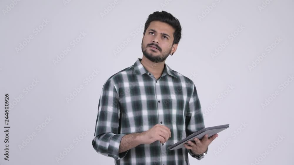 Portrait of young happy bearded Indian man using digital tablet Portrait of young happy bearded Indian man using digital tablet