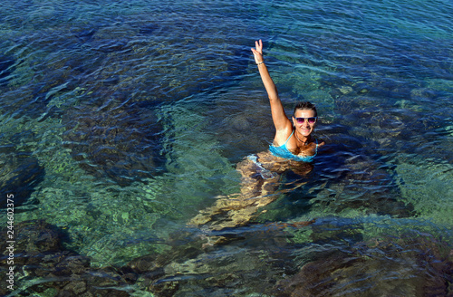 A young woman in swimsuit floats in seawater