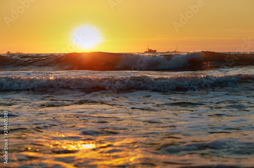 Sunset over the sea. Reflection of sunlight in the sea waves. Red and yellow sky in the rays of the sunset.