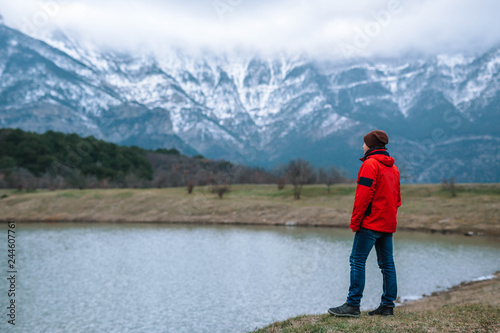 A young tourist looks at the picturesque landscape of snow-capped mountains.