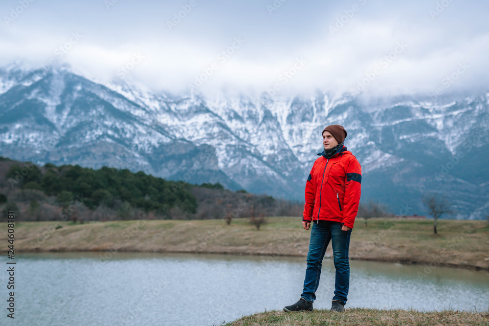 A young tourist looks at the picturesque landscape of snow-cappe