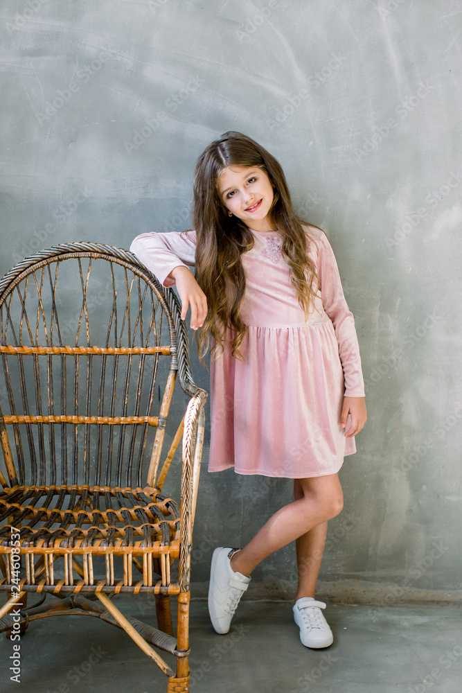 Cute baby girl 5-6 year old wearing stylish pink dress overgrey background.  Looking at camera. Birthday party. Celebration. Stock Photo | Adobe Stock