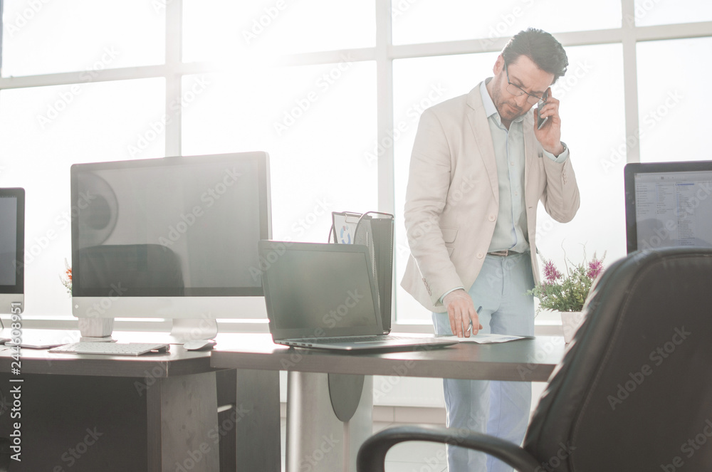 businessman working on a calculator standing in a bright office