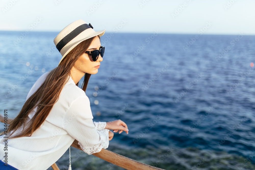 Young prety woman in straw hat and sunglasses on pier in stylish elegant clothes poses enjoying amazing view. Young prety woman in straw hat and sunglasses on pier in stylish elegant clothes poses enjoying amazing view.