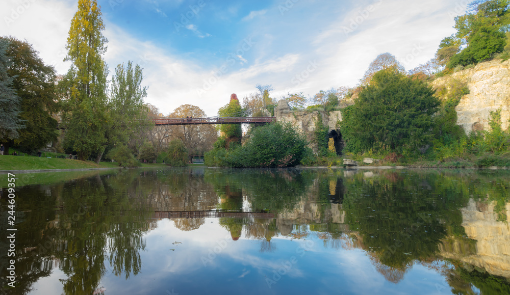 Fototapeta premium Paris, France - 11 03 2018: Neighborhood of Villette. The park Buttes-Chaumont. Island with a bridge and reflects on the water