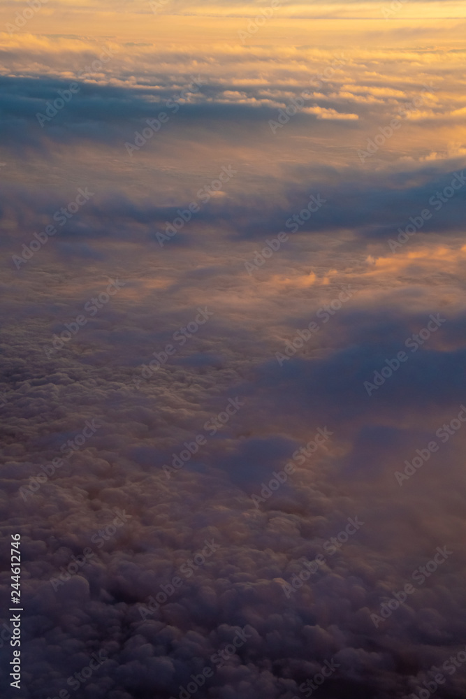 Cloud cover illuminated by sunset half orange and half in earth shadow