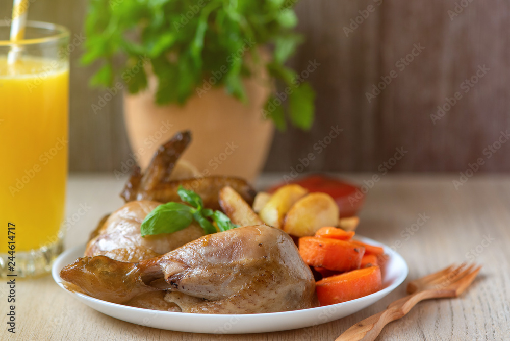 Roasted chicken, potatoes and vegetables in white plate on wooden background